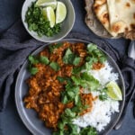 A plate of vegan curry with rice on a dark background.