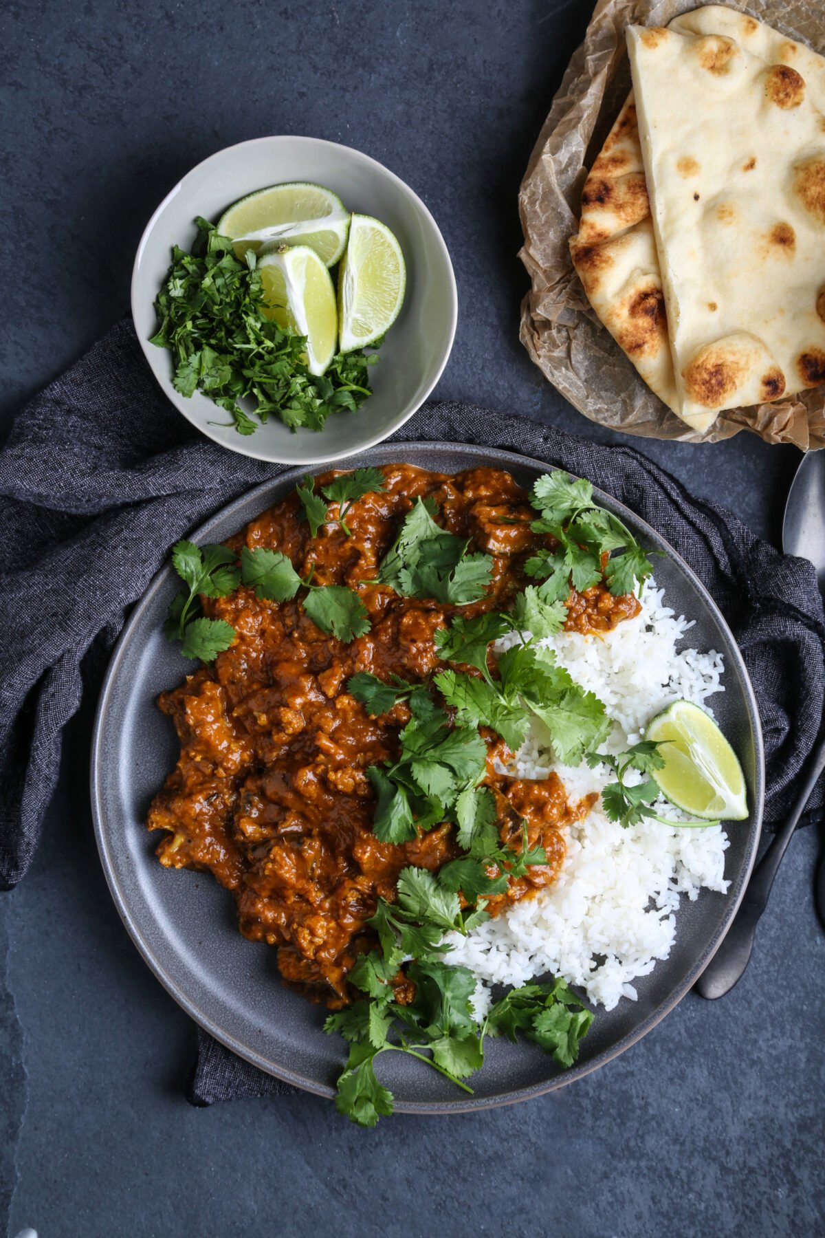 A plate of cauliflower curry with naan and fresh cilantro.