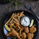 Deep-fried jackfruit, served on a black plate with fries.