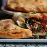 A homemade vegan calzone, cut open to show its interior.