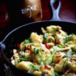Crispy General Tso’s cauliflower in a black skillet, coated in sticky ginger-garlic sauce and topped with scallions, chilies, and peanuts.