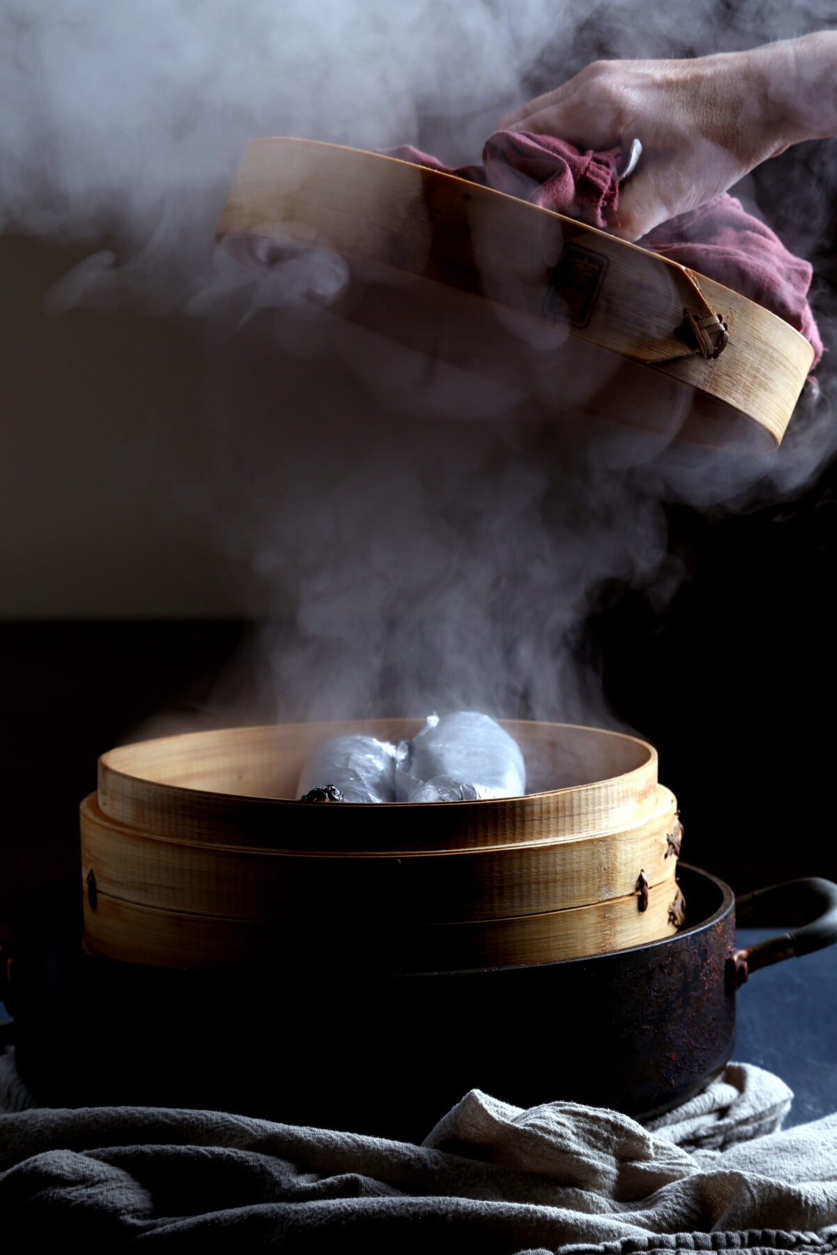 A steamer basket with lots of steam rising up from it.