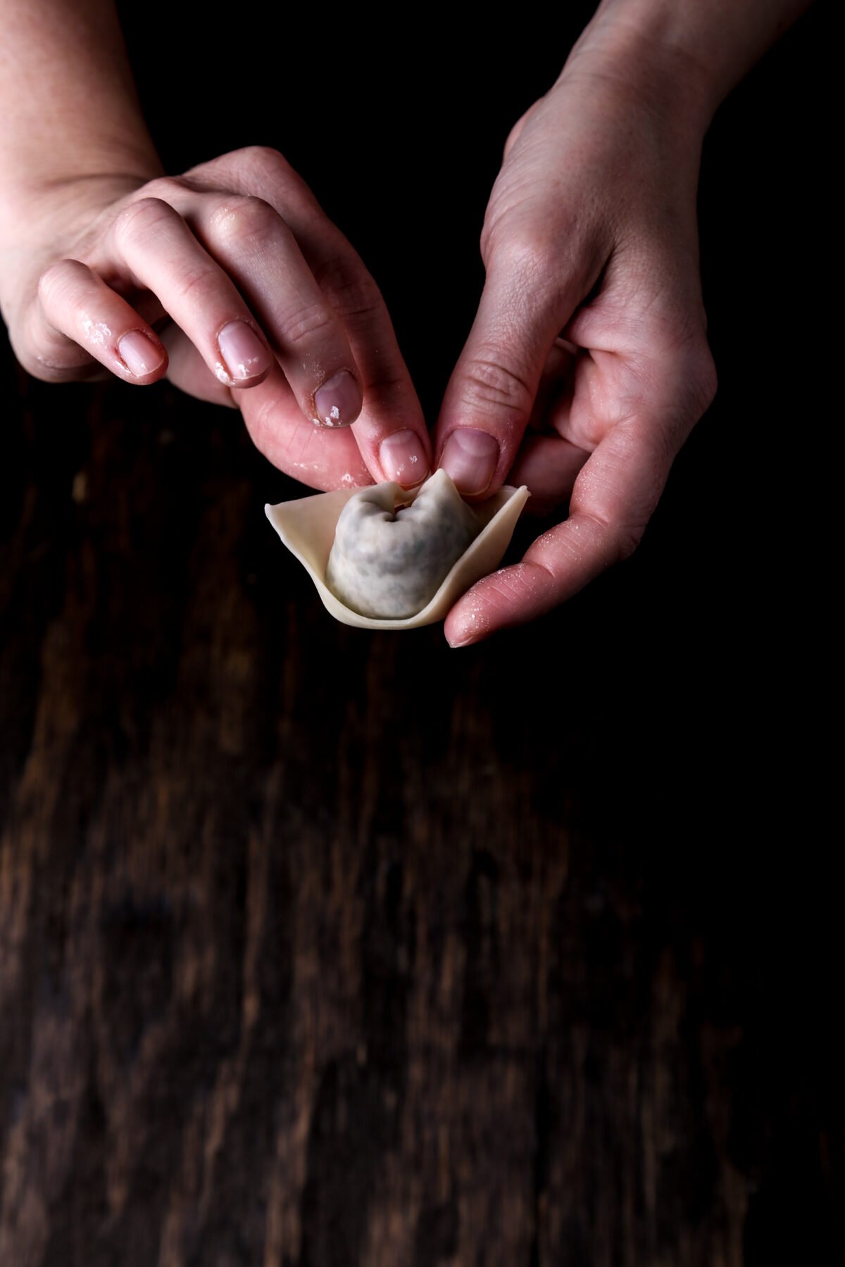 A hand folding a wonton.