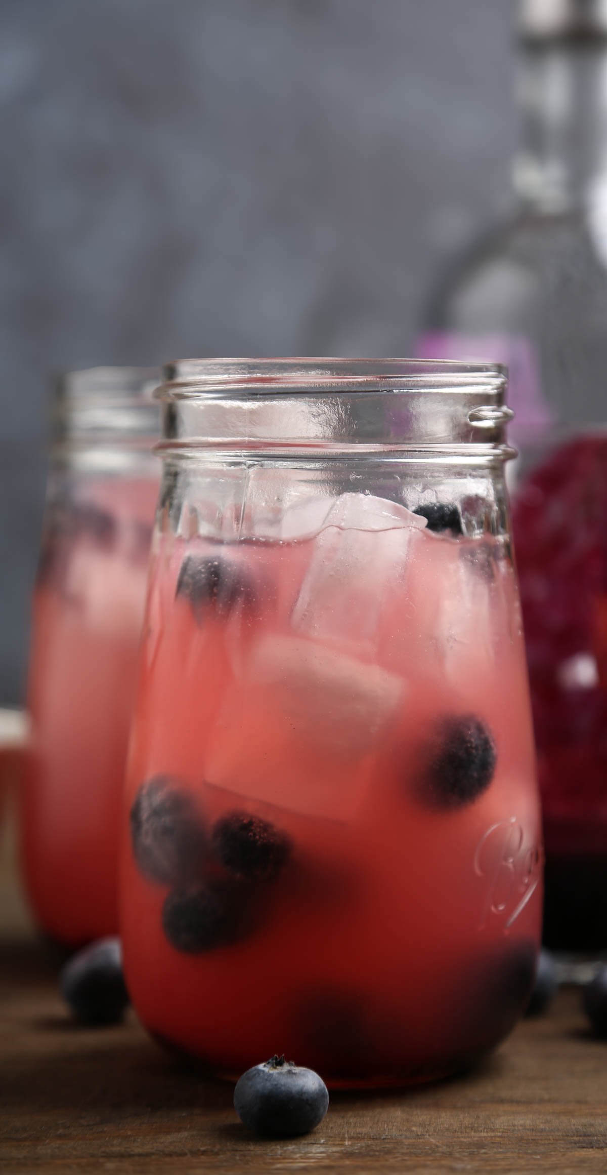 A glass of kombucha with blueberries.