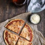 A top-down shot of a quinoa crust pizza that's been cut into four pieces.