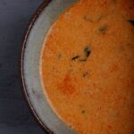 A bowl of red curry sauce.