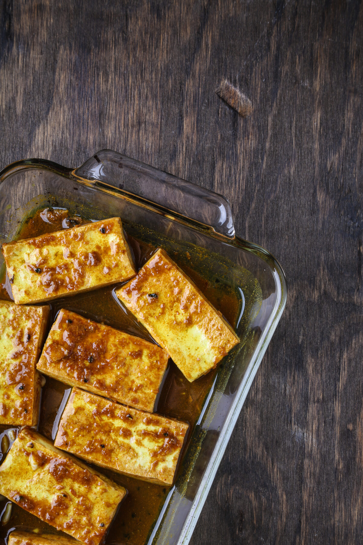 Tofu in a glass pyrex in a marinade.