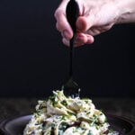 A plate of fettuccine coated in rich, creamy vegan alfredo sauce, garnished with fresh chives and lemon zest, ready to be twirled on a fork.