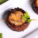 A vegan bacon-wrapped scallop with garnish.