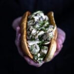 A vegan lobster roll held in two hands.