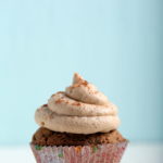 A vegan pumpkin cupcake, topped with frosting.