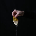 Vegan queso dip on a chip against a dark background.