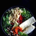 A vibrant bowl of vegan ramen with crispy tofu, bok choy, shiitake mushrooms, and fresh toppings, served with a rich umami broth.